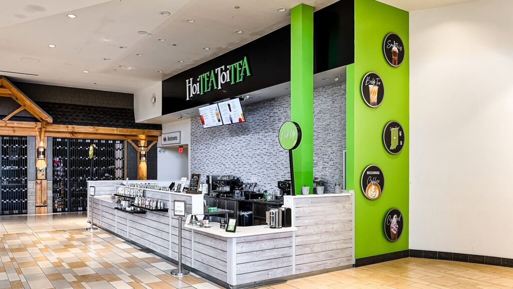 Tea counter area with sleek gray wood paneling and illuminated HoiTea ToiTea branding.