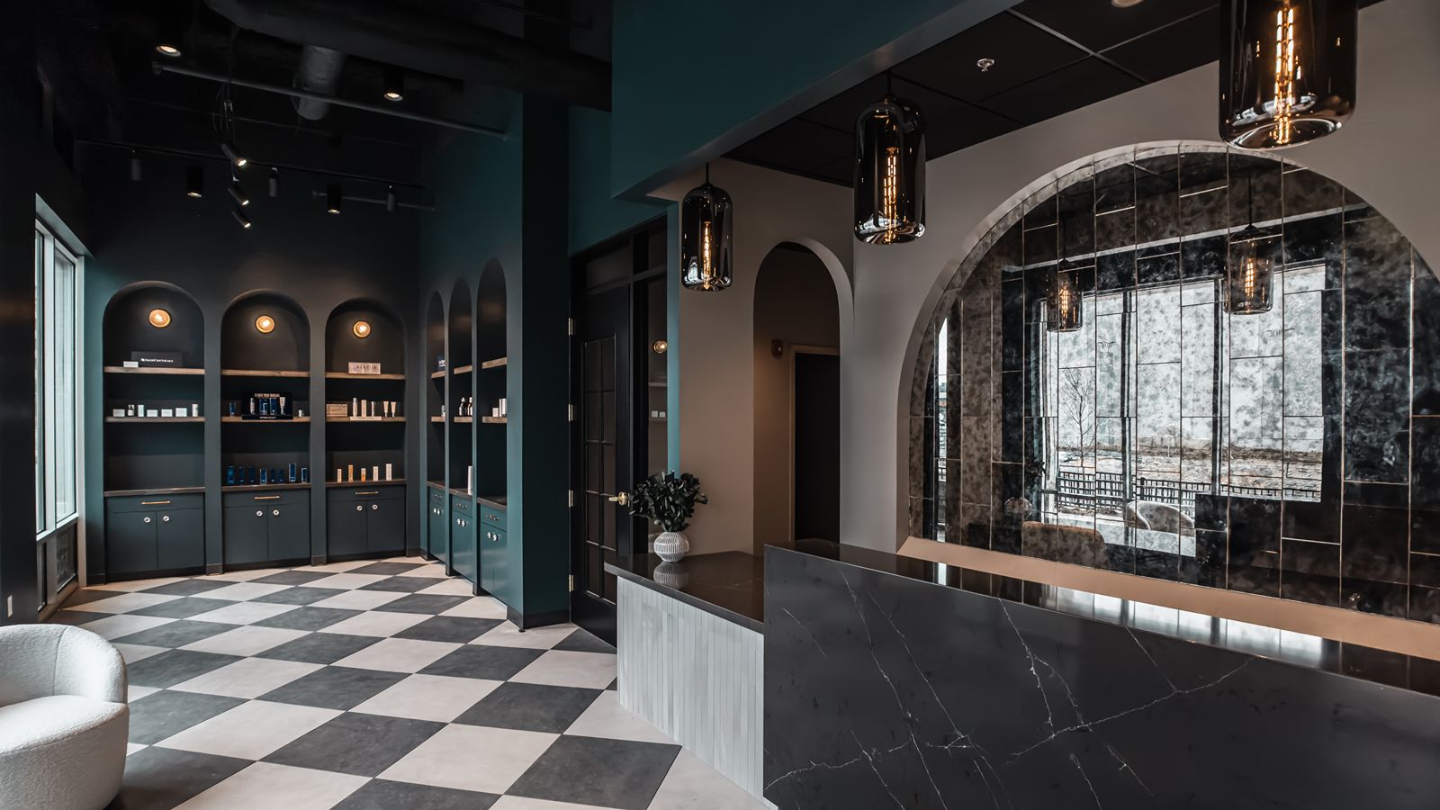 Reception area featuring black marble counter, arched mirrored wall, and luxury med spa design.