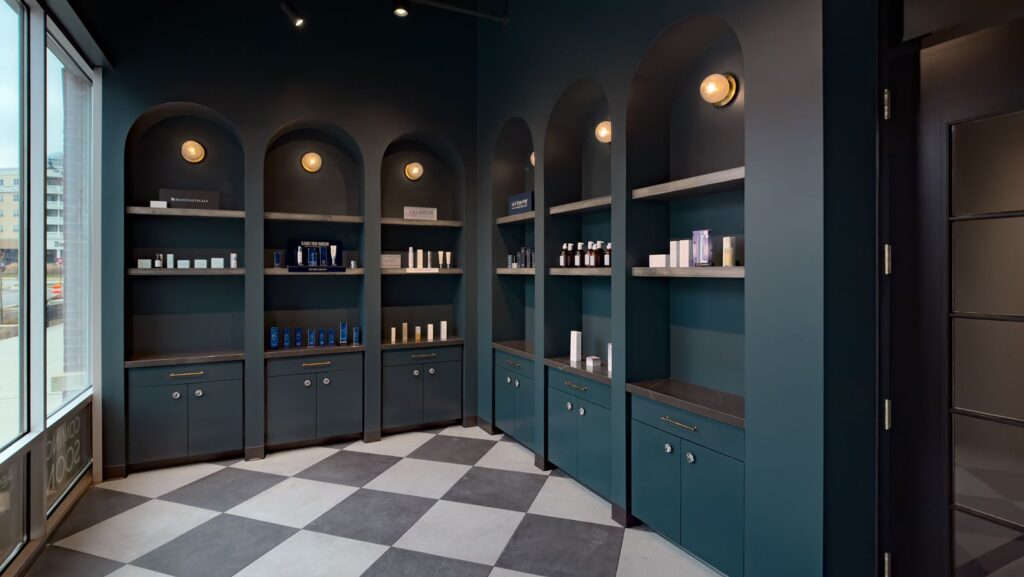 Product display wall with arched shelving and accent lighting in luxury skincare studio.