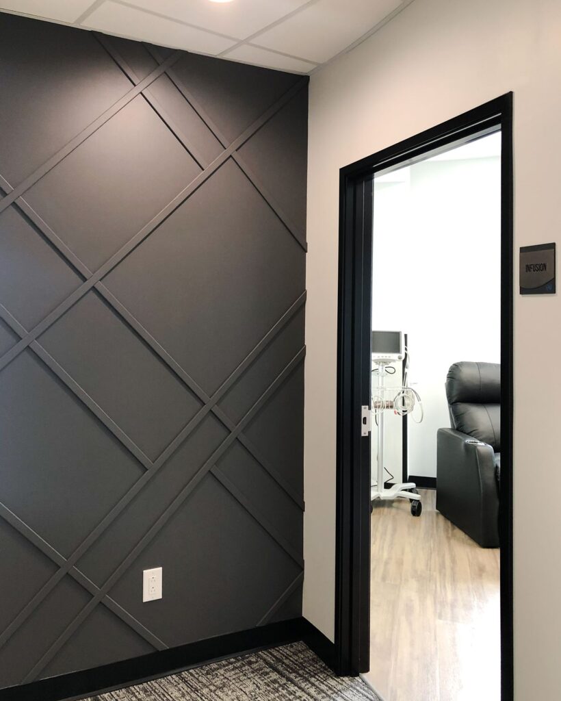 Accent wall with geometric paneling and modern hallway design by healthcare architecture firm.