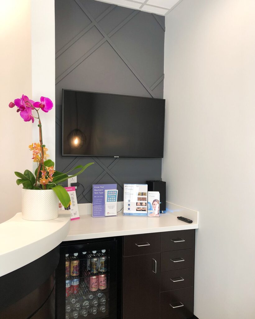 Reception area with orchid arrangement and built-in television designed for welcoming patient experiences.