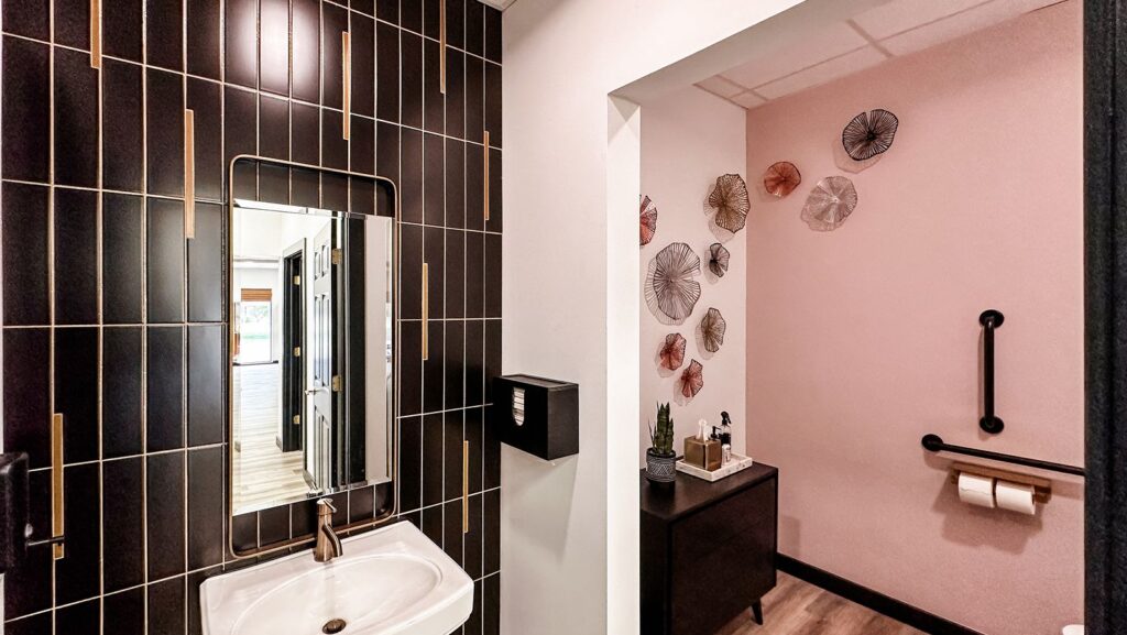 Modern restroom with black tile wall and sleek mirror design.