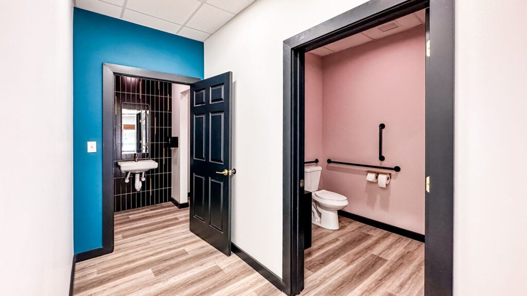 Accessible restroom featuring pink walls and dark trim details.