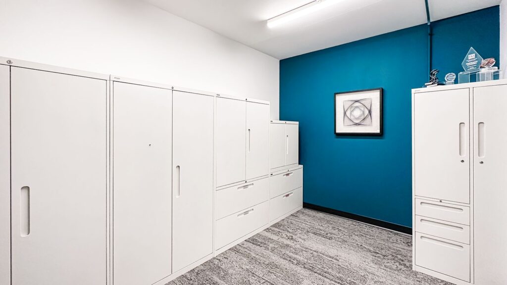 Hallway with white storage cabinetry and blue accent wall in modern office design.