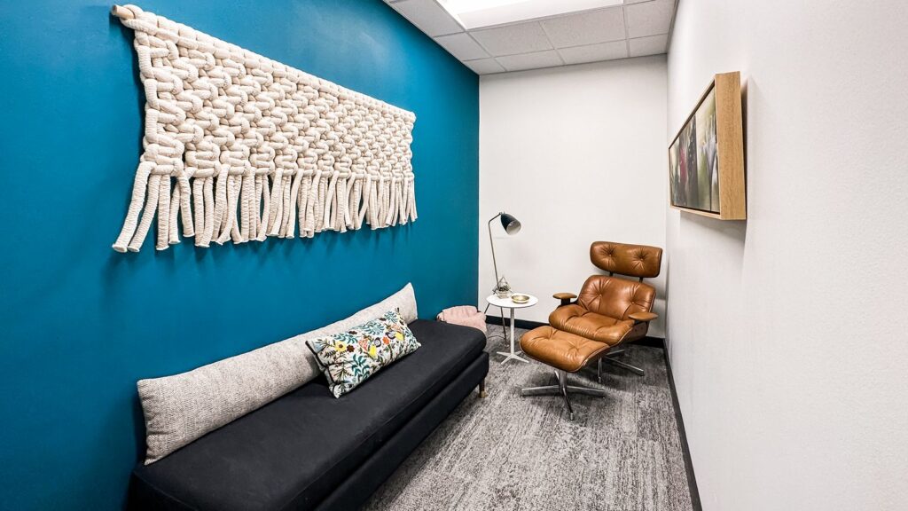 Private office with blue accent wall, gray sofa, and leather lounge chair.