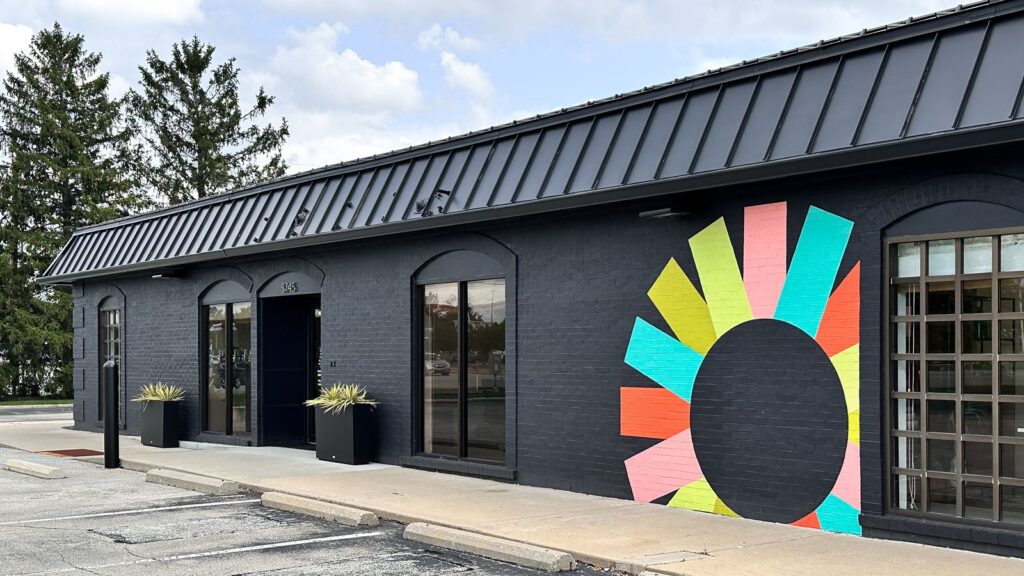 Exterior view of Insite Art Consultants building with black painted brick and colorful mural.