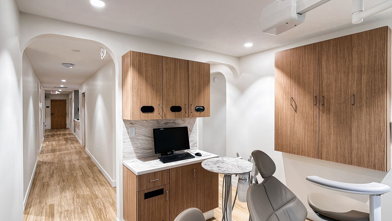 Hallway with warm wood flooring and built-in cabinetry in modern dental office renovation.