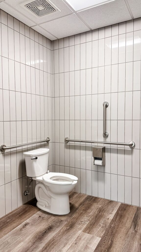 Accessible restroom featuring vertical tile walls and ADA-compliant fixtures designed through modern office architecture planning.