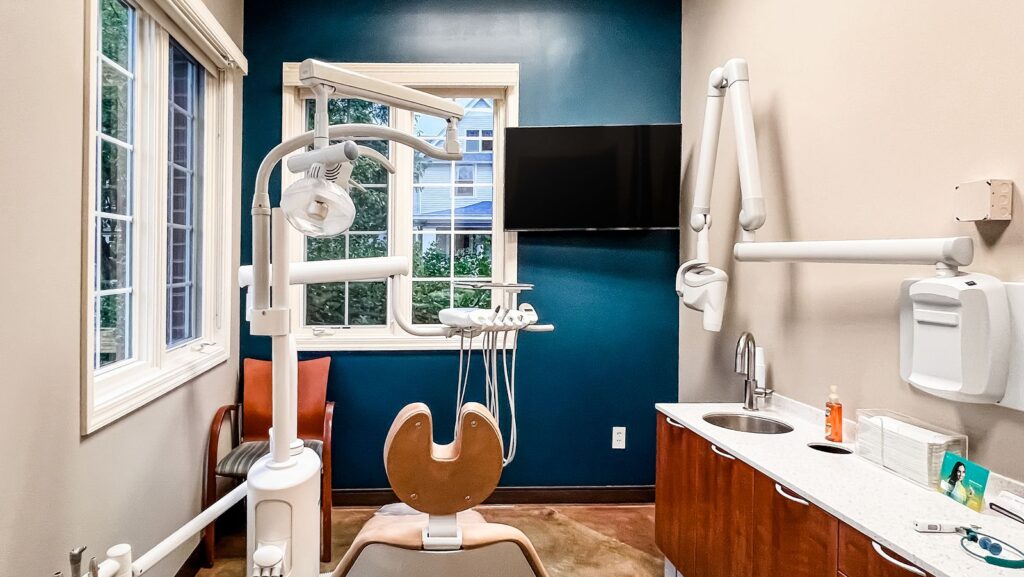 Exam space with dental chair, cabinetry, and blue feature wall.