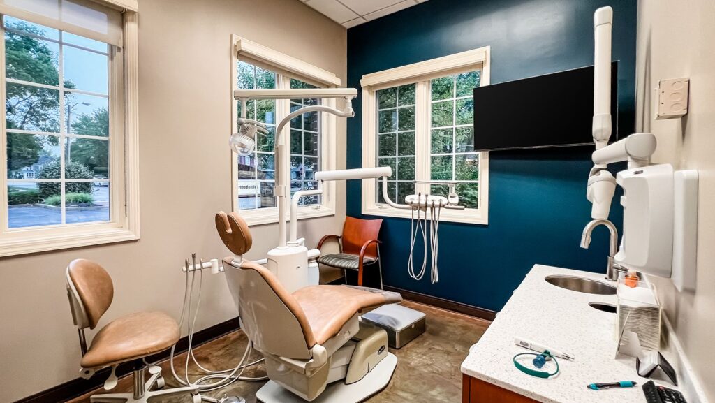 Dental operatory with tan chair, blue accent wall, and large windows.