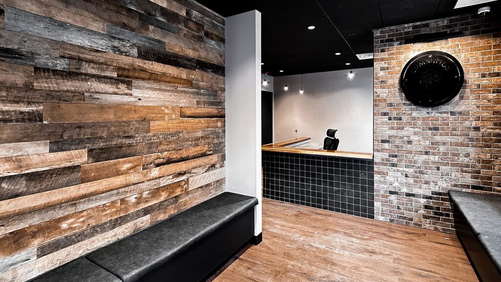 Reception entry with reclaimed wood wall and bench seating designed for a modern dental clinic remodel.