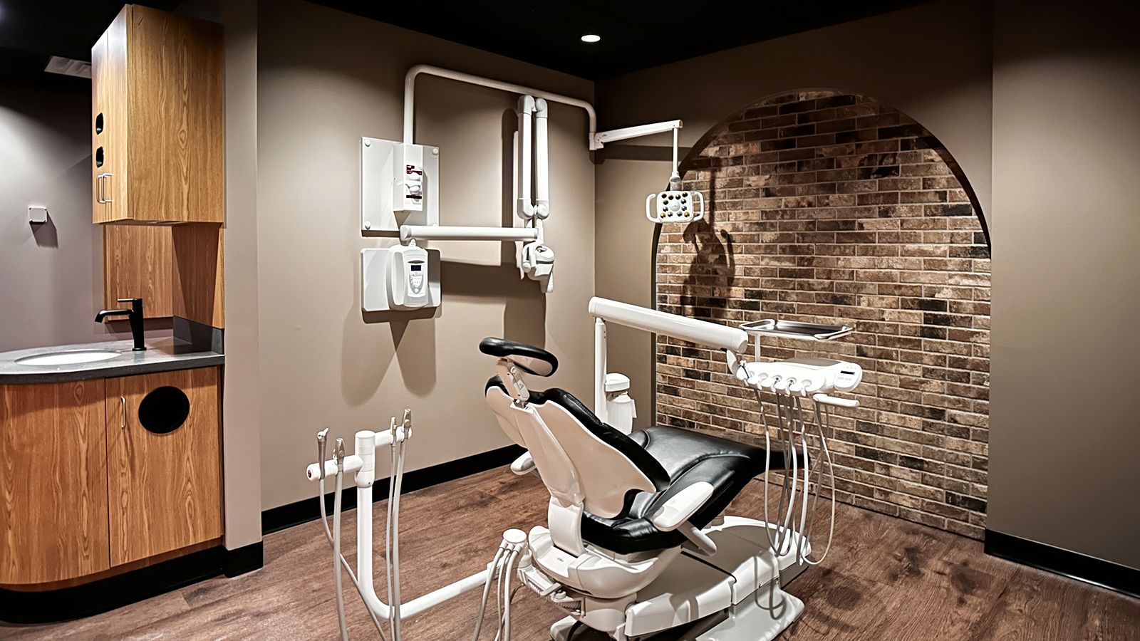 Dental treatment room featuring brick accent wall and modern dental office design by healthcare architects.