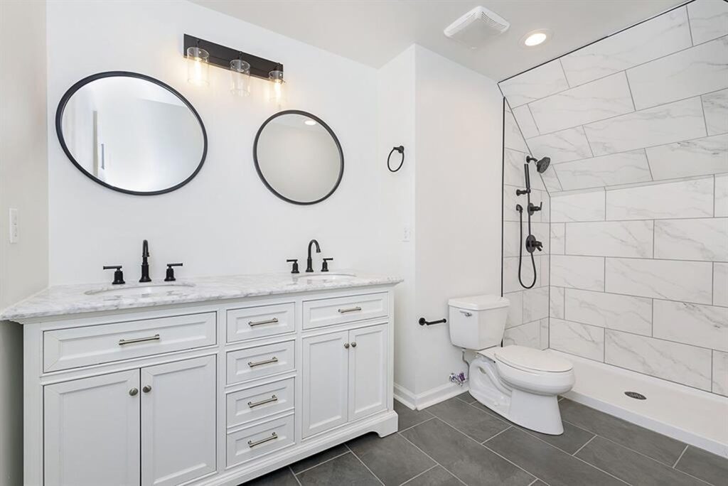 Contemporary bathroom with dual mirrors and white vanity design.