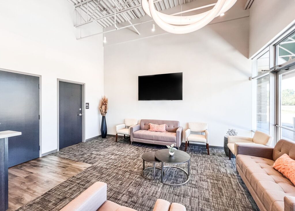 Lobby interior featuring modern seating, open ceiling design, and large entry windows.