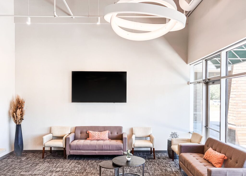 Lobby interior featuring modern seating, open ceiling design, and large entry windows.