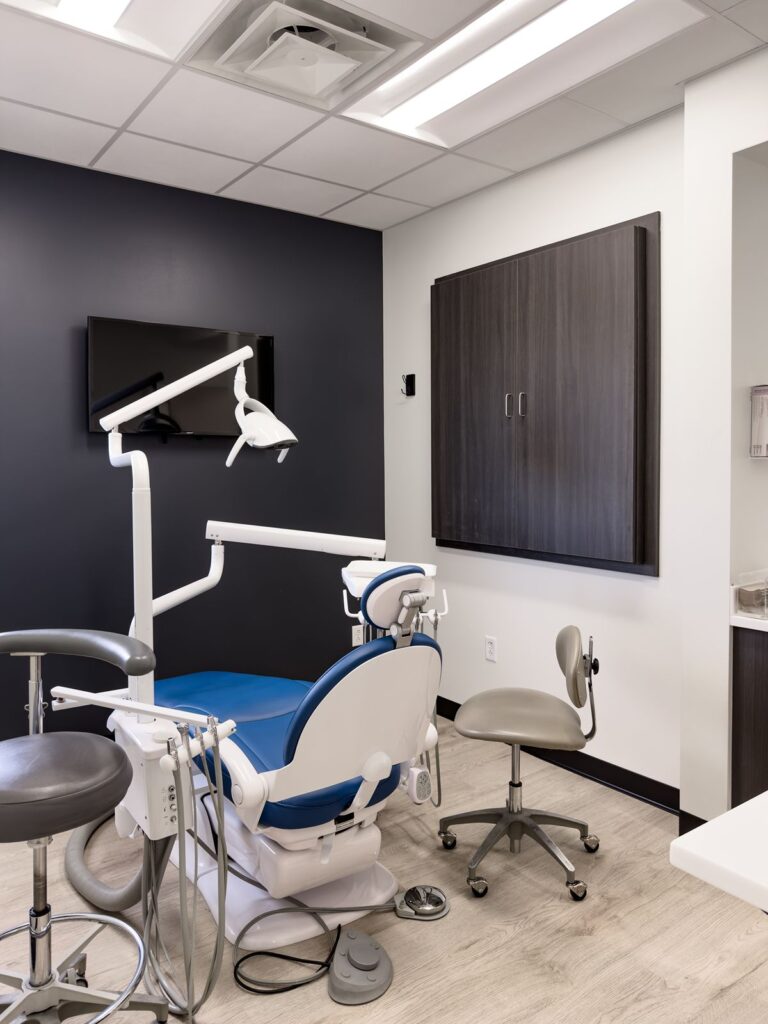 Dental treatment room with chair and mounted monitor.