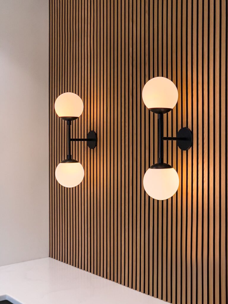 Wall sconce lighting detail on vertical wood slat accent wall.