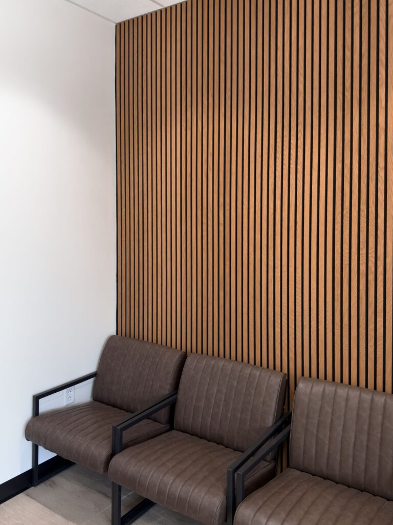 Waiting area with wood slat wall and brown leather chairs.