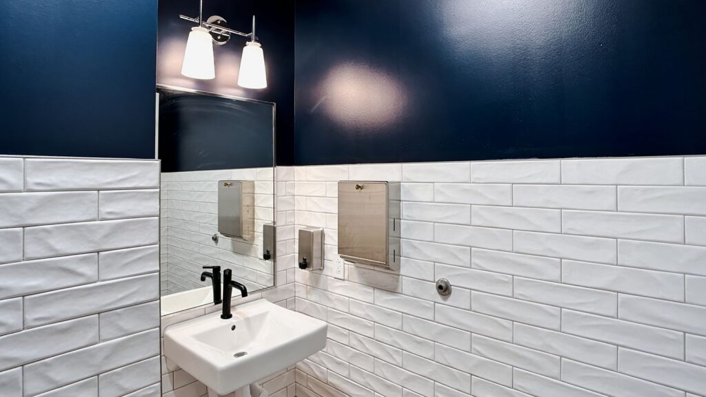 Restroom with navy accent wall and white subway tile.