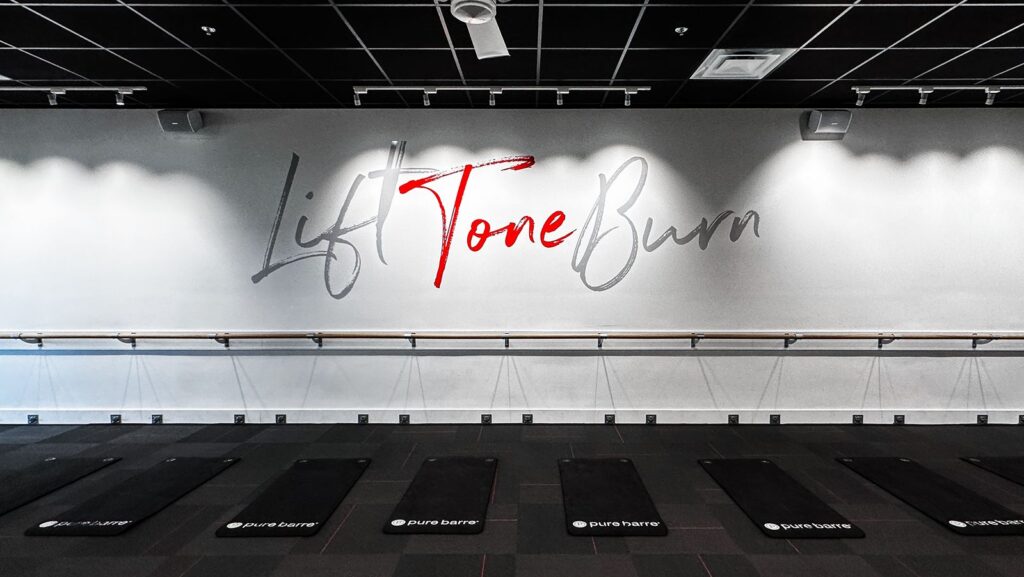 Studio wall design with “Lift Tone Burn” lettering and ballet bar installation.