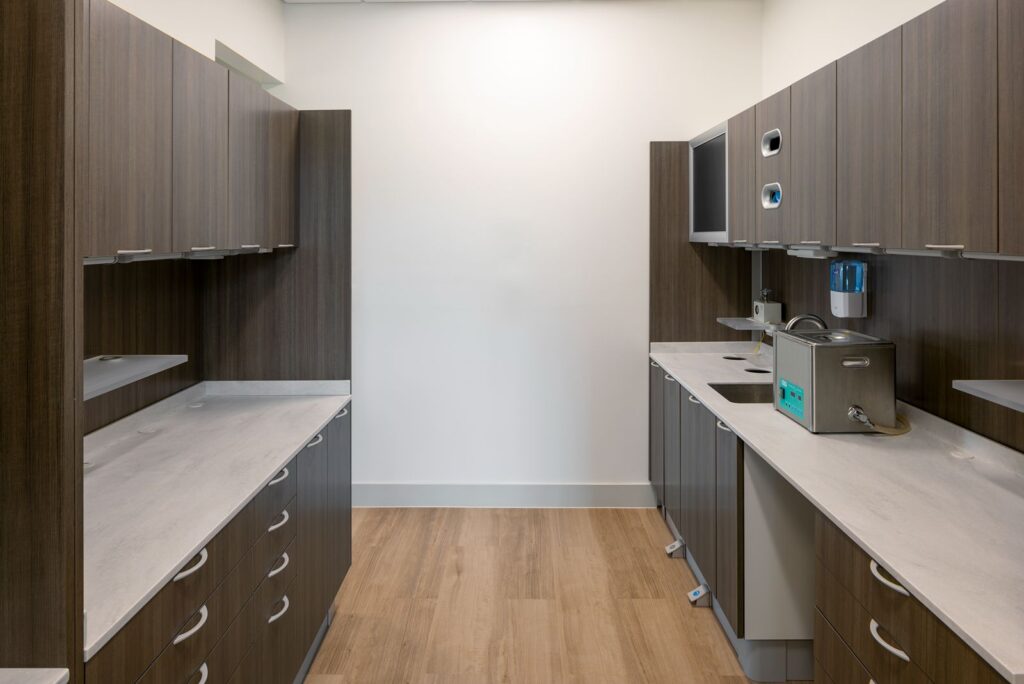 Dental treatment room with black dental chair, cabinetry, and minimalist healthcare interior design.