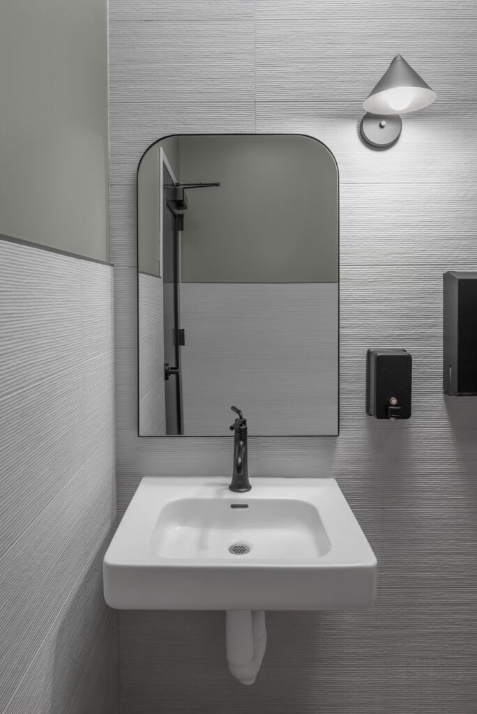 Restroom design featuring sleek wall tile, mirror, and modern medical interior design details.
