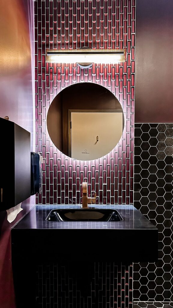 Close-up of powder room design featuring black hex tile and modern lighting details.