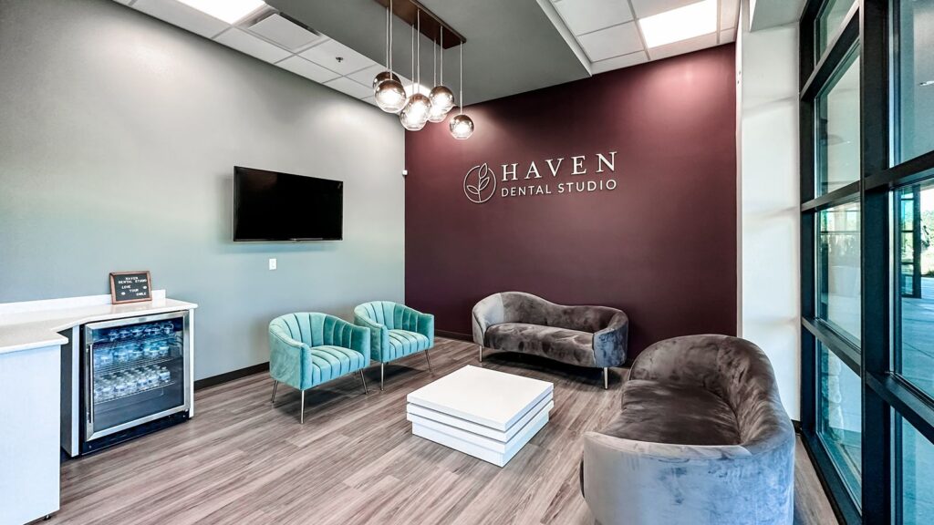 Reception area with teal seating and branding wall showcasing modern dental studio interior design.