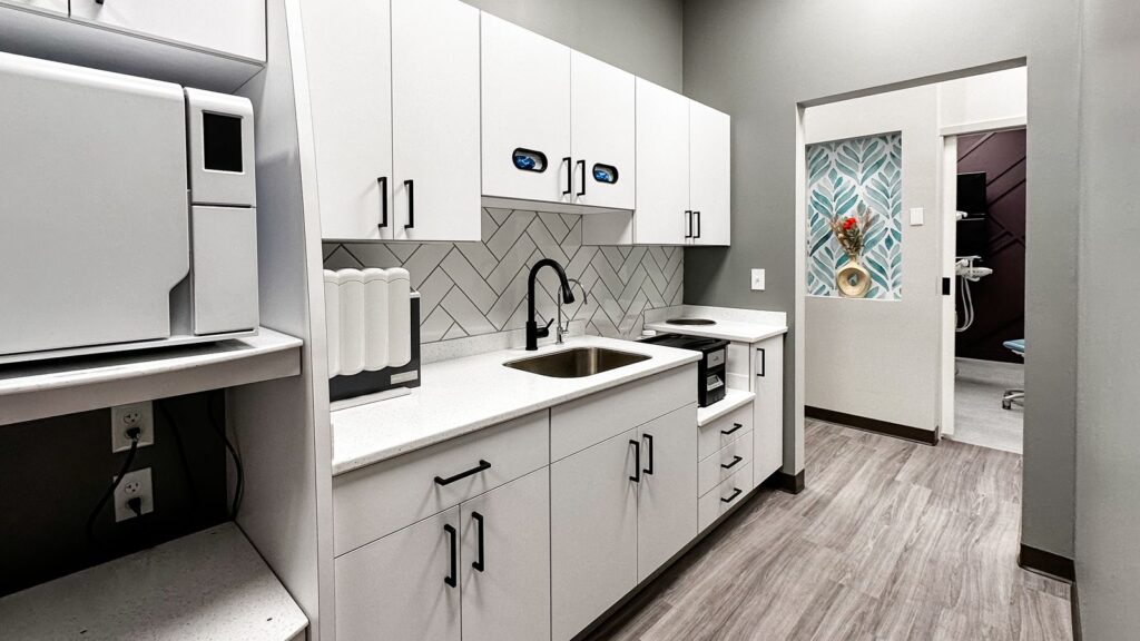 Dental lab featuring white cabinetry and herringbone backsplash for modern clinical flow.
