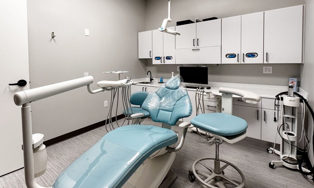 Operatory with deep plum feature wall and mounted TV for patient comfort.