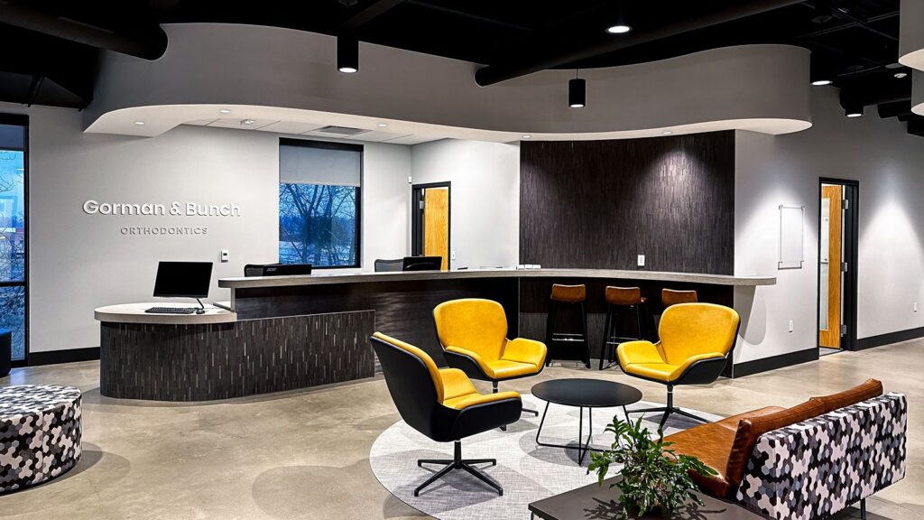 Reception area with curved desk, warm lighting, and modern orthodontic office design by healthcare architects.