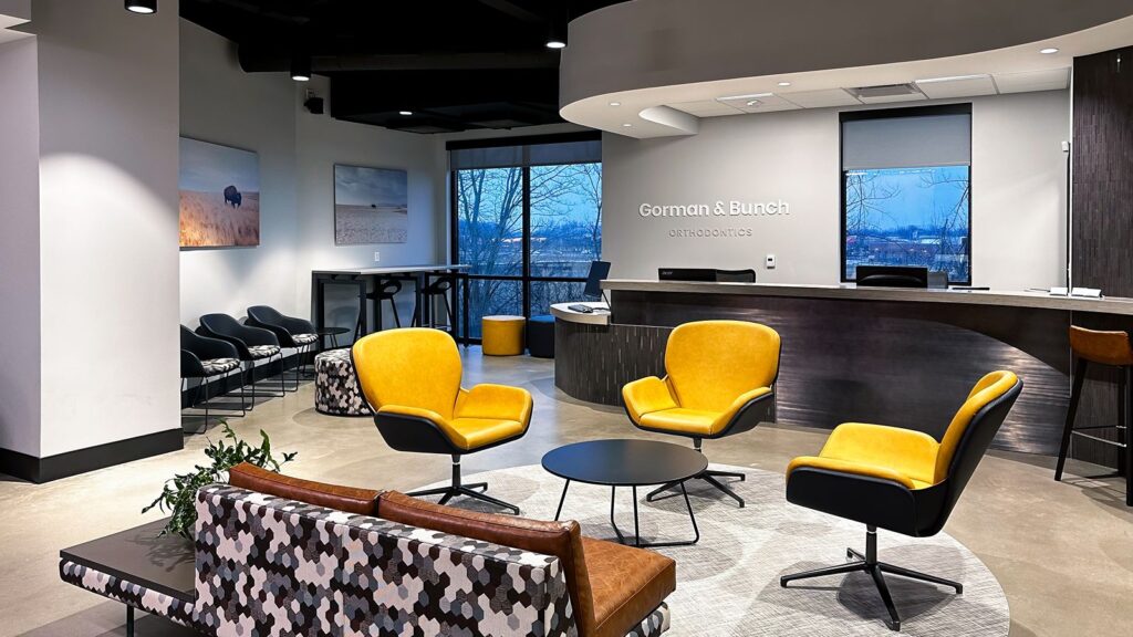 Lobby seating area with yellow chairs and neutral finishes in modern orthodontic practice.