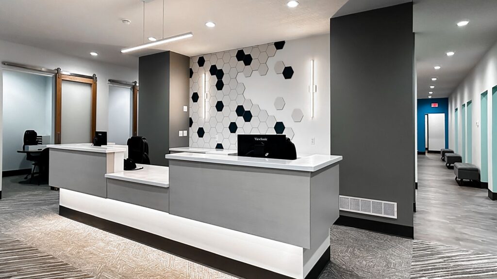 Reception desk with geometric wall design and modern lighting.