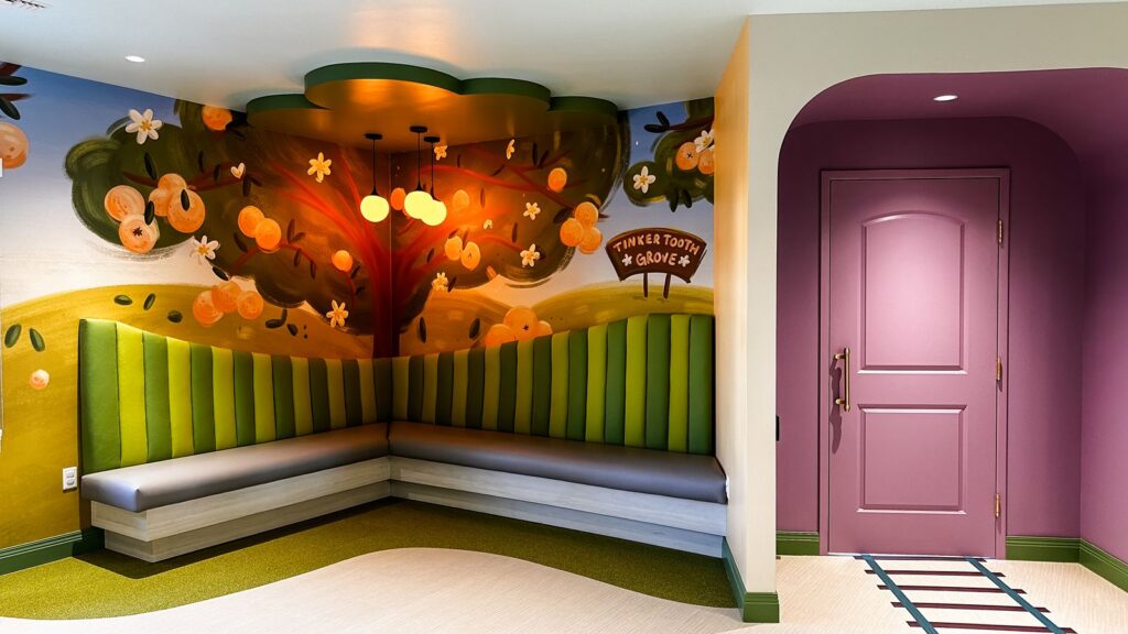 Whimsical lobby with tree-themed mural and curved seating designed by pediatric dental office designers in Indiana.