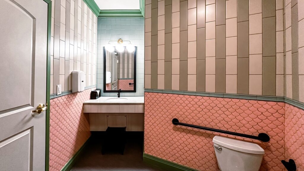 Restroom featuring coral and beige tile walls designed by dental architects with modern accessibility features.