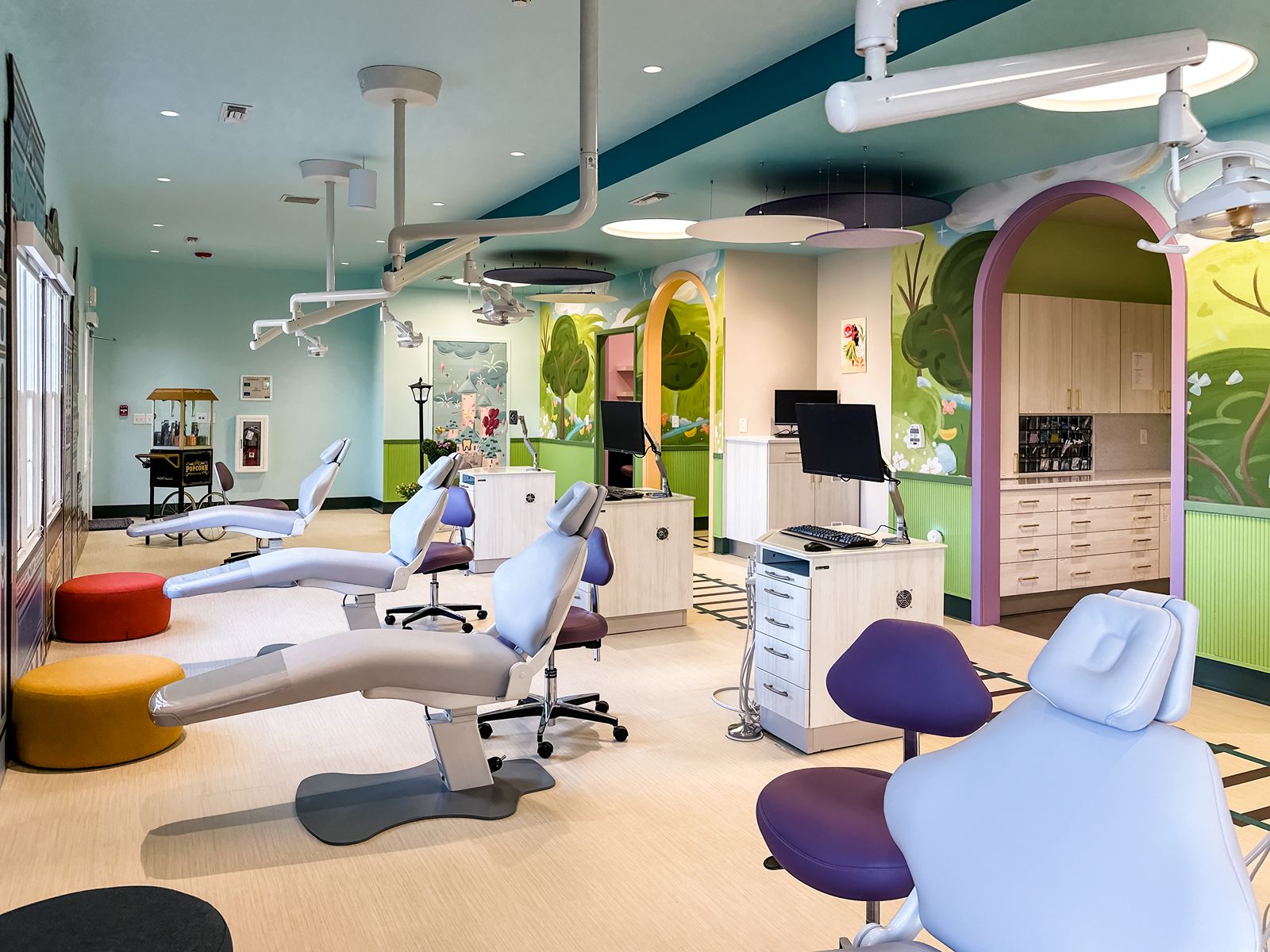 Open dental bay featuring storybook-style wall murals designed by dental architects for a child-friendly experience.