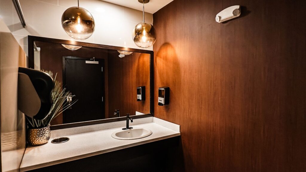 Restroom interior featuring warm wood walls and globe pendant lighting.
