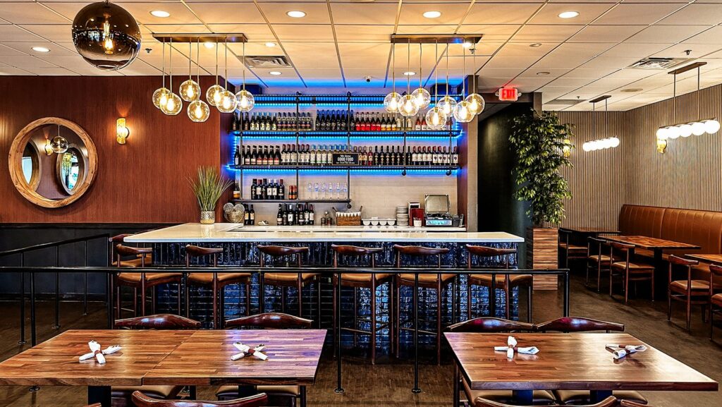 Contemporary bar design with bottle display, marble countertop, and blue backlighting.