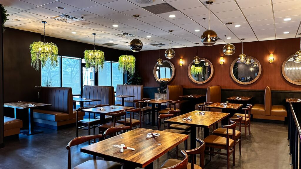 Wide-angle of dining room featuring hanging greenery and warm leather seating.