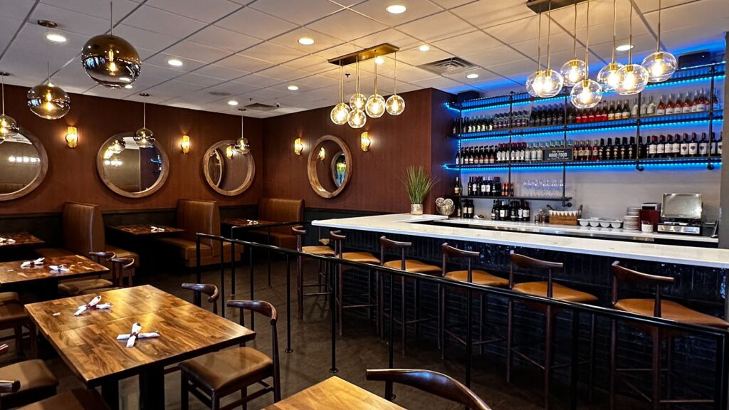 Dining area of Thai Season Restaurant featuring modern lighting, rich wood finishes, and blue accent bar.