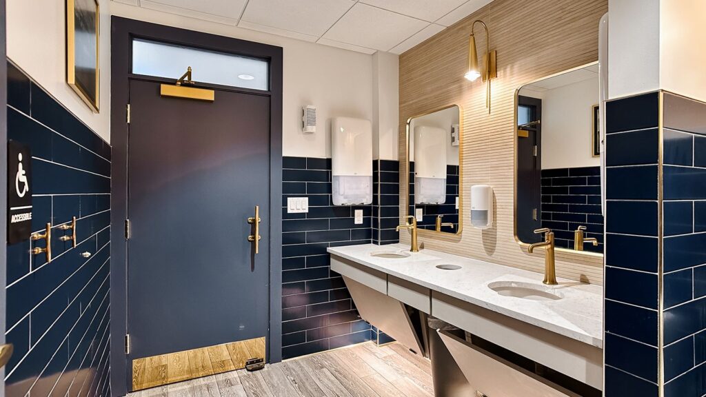 Navy and white restroom design with gold fixtures and framed artwork.