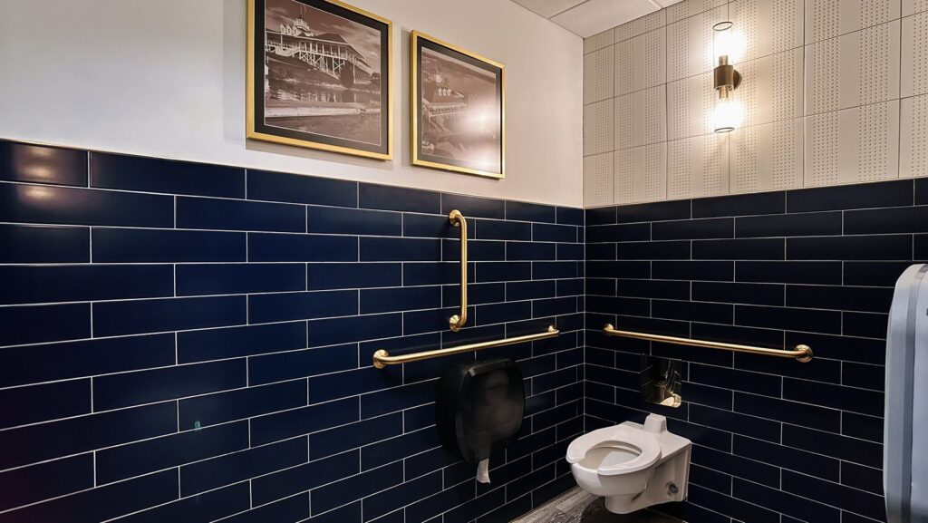 Navy and white restroom design with gold fixtures and framed artwork.
