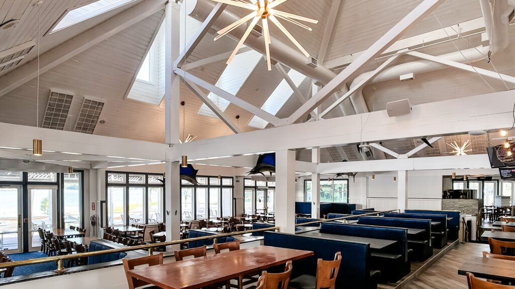 Navy booths and wooden tables under vaulted white beams.